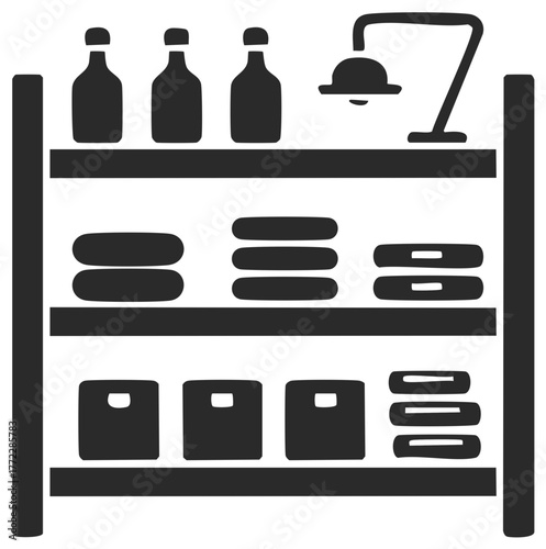 Shelving unit with storage boxes, folded items, bottles, and a lamp