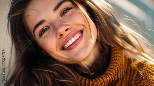 She has long brown hair that is slightly wind-swept, noticeable freckles, and striking green eyes. She is wearing a chunky, orange-brown turtleneck sweater.
