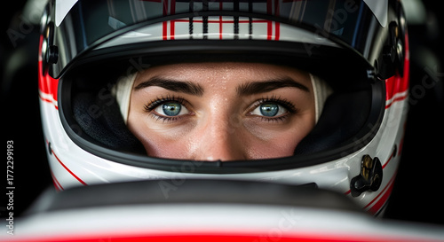 The female race car driver is focused, ready to start and win the race as she sits inside the car during the competition