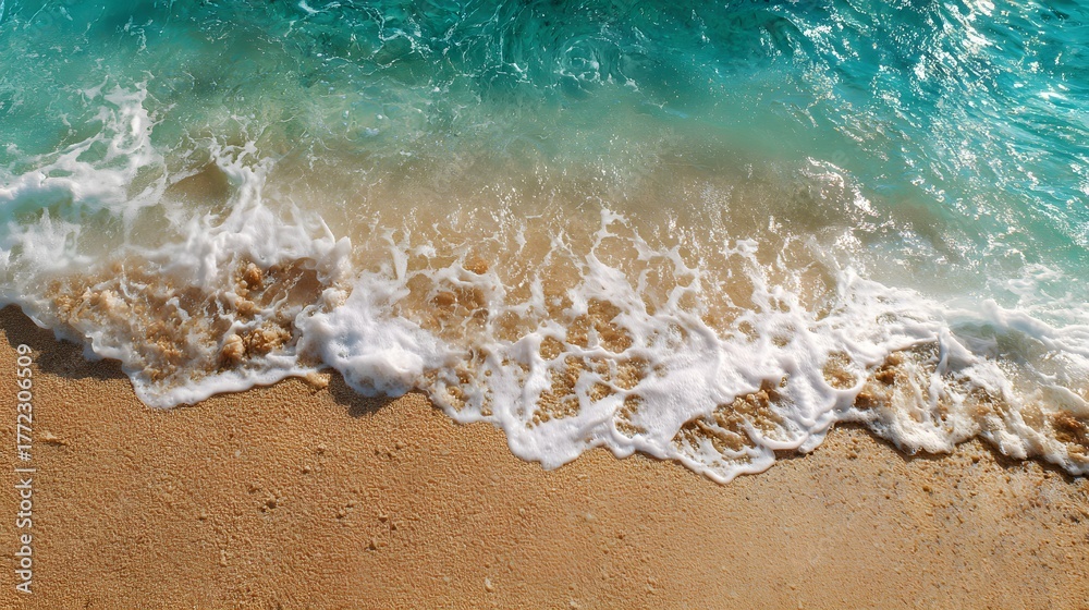 Obraz premium Aerial view captures foamy ocean waves washing onto a golden sandy shore
