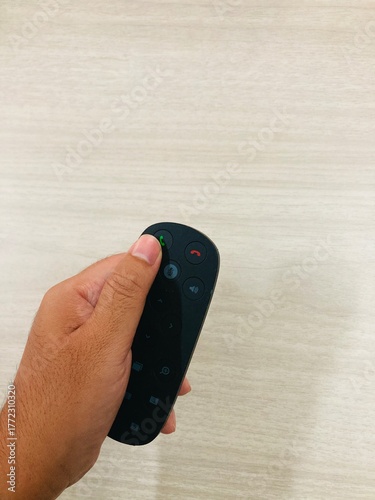 Hand holding conference remote control on wooden desk