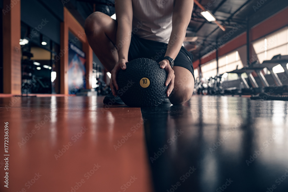 Fototapeta premium Young Asian man doing fitness workout with med ball in gym.