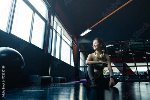 Woman, gym and exercise relax on floor for training break or fitness recovery, thinking or self care.
