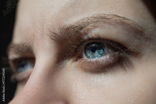 Blue eye close up with natural eyelashes and soft skin texture. Studio portrait, shallow focus.