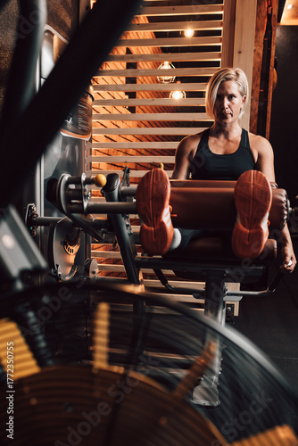 Caucasian fitness woman using a leg press machine in a gym, focused workout