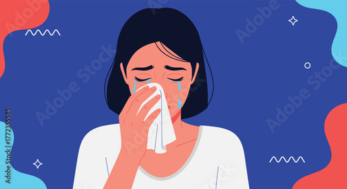 A young woman is crying with tears on her face, using a tissue to wipe her nose, expressing deep sadness, grief, and emotional distress.