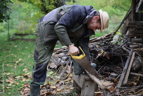 Photos country man cutting wood with a saw