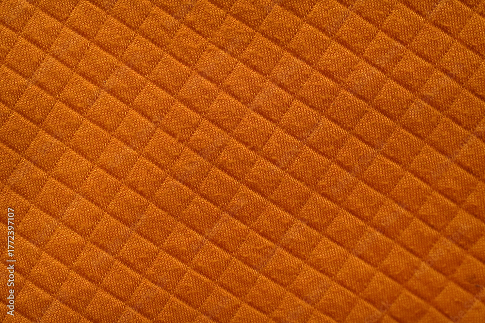 Obraz premium Close-Up of Orange Quilted Fabric with Diamond Stitch Pattern