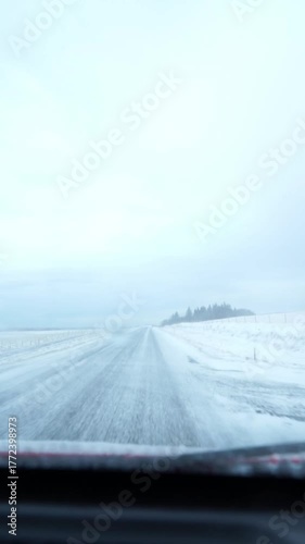 Car driving down a snowy rural road in winter