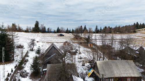 Photography A tranquil winter panorama of Beskid Mały in southern Poland, where snowy meadows meet evergreen forests and rolling mountain hills under a serene, cloud-streaked sky