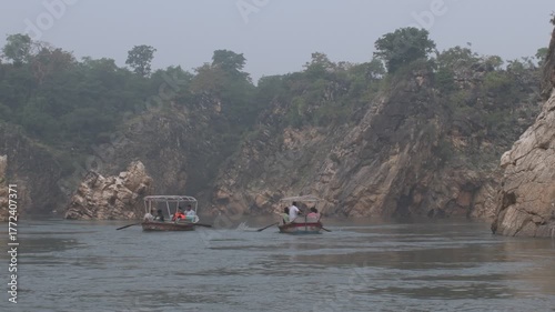 scenic river gorge with boats rowing between towering marble rock cliffs and deep calm flowing water surrounded by nature, marble rocks, jabalpur, india