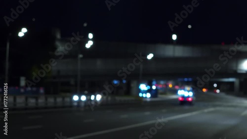 Abstract blurred night city road with moving cars, glowing headlights and soft bokeh lights creating a moody urban atmosphere