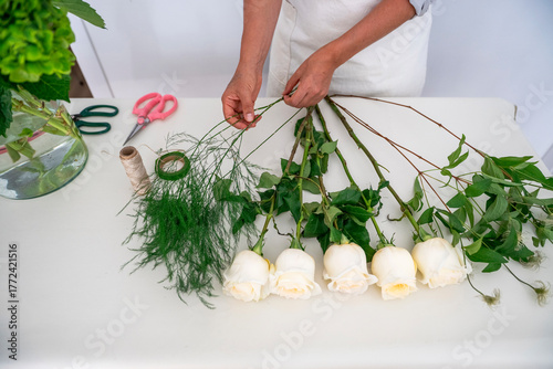 Florist hands arranging white roses for bouquet
