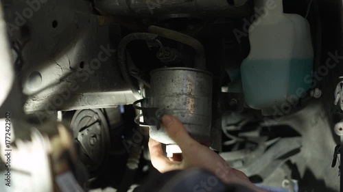 The master removes the fuel filter from the holders in the car. Home self-repair of the car. Evening atmosphere, professional light