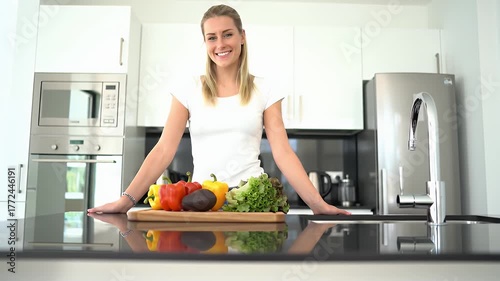 Smiling Woman With Blonde Braids In A Modern White Kitchen Posing With Fresh Vegetables On A Countertop