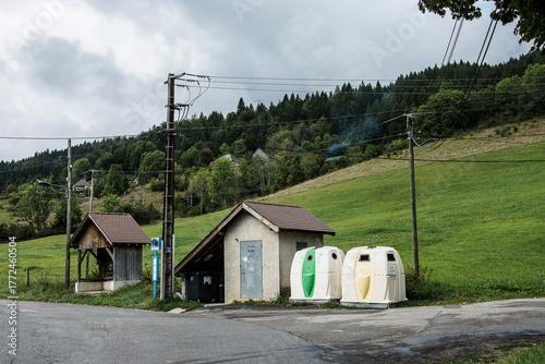 bus stop and municipal waste depot with containers for glass and paper near a few lampposts in the hills of the French Chartreuse regio