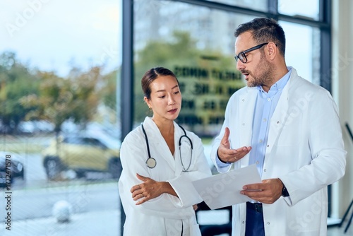 Fotografía Asian Woman Doctor and Caucasian Doctor Discuss Medical Document in a Clinic