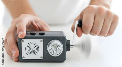 Hands turning the crank on a handpowered emergency radio and flashlight.