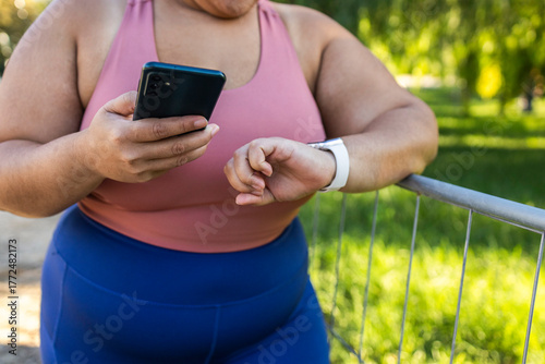 Woman checking fitness app on smartphone and smartwatch