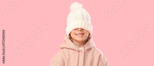 Cute little Asian boy in white knitted hat on pink background