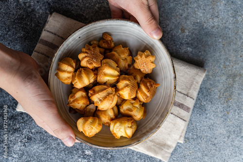Homemade caramel profiteroles in ceramic bowl held by hands
