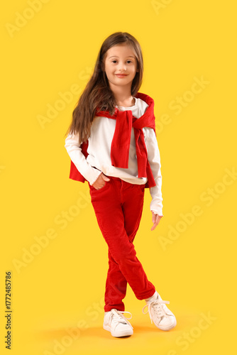 Little girl in winter clothes on yellow background