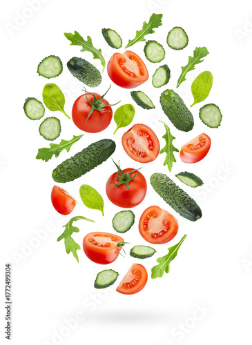 Bright vegetable salad ingredients - red tomato, green cucumbers, greens -  fly or fall as flow art composition, isolated. Wholesome, vitamin ingredient for antioxidant salads, healthy dietary menus.