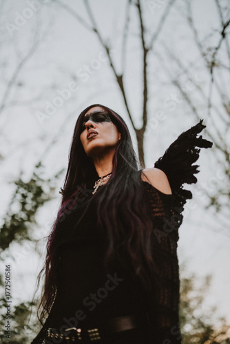 woman dressed and made up as a black angel with wings in the nature