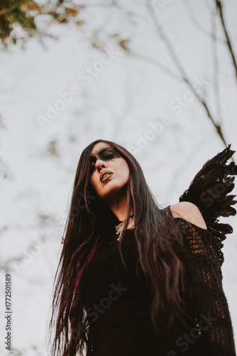woman dressed and made up as a black angel with wings in the nature