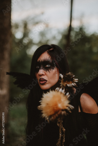 woman dressed and made up as a black angel with wings in the nature