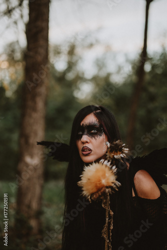 woman dressed and made up as a black angel with wings in the nature
