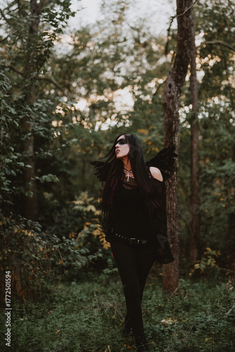 woman dressed and made up as a black angel with wings in the nature