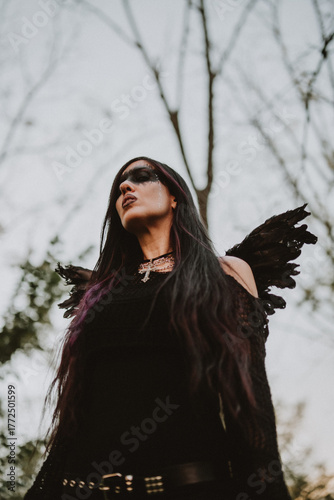 woman dressed and made up as a black angel with wings in the nature