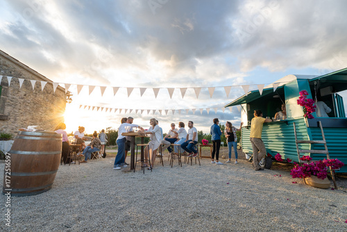 Friends enjoying drinks at outdoor food truck party at sunset