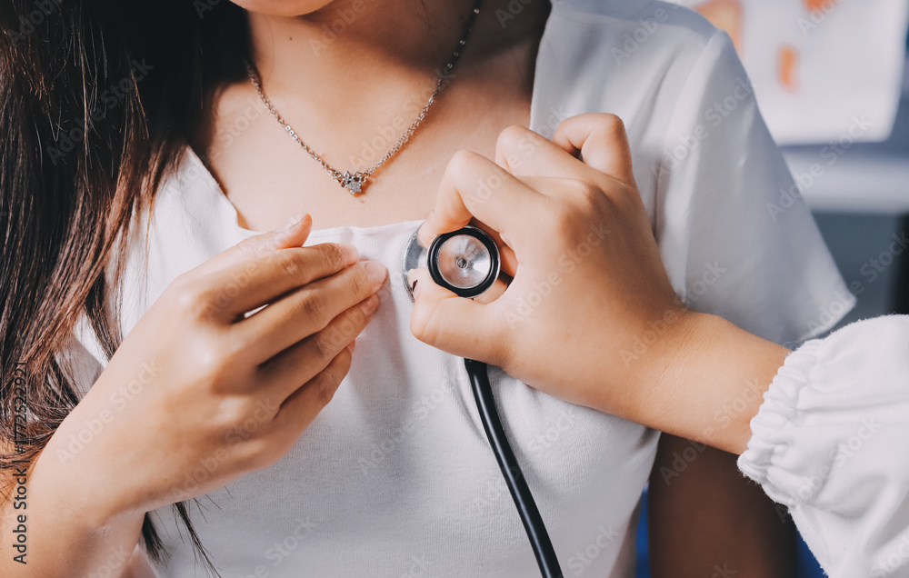 Fototapeta premium Doctor examining patient with stethoscope in hospital bed. Medical care and healthcare concept in a clinical setting.