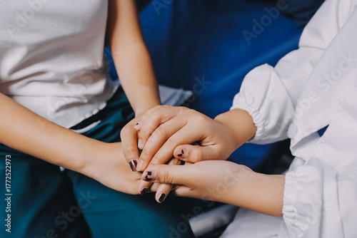 Doctor giving hope. Close up shot of young female physician leaning forward to smiling elderly lady patient holding her hand in palms. Woman caretaker in white coat supporting encouraging old person