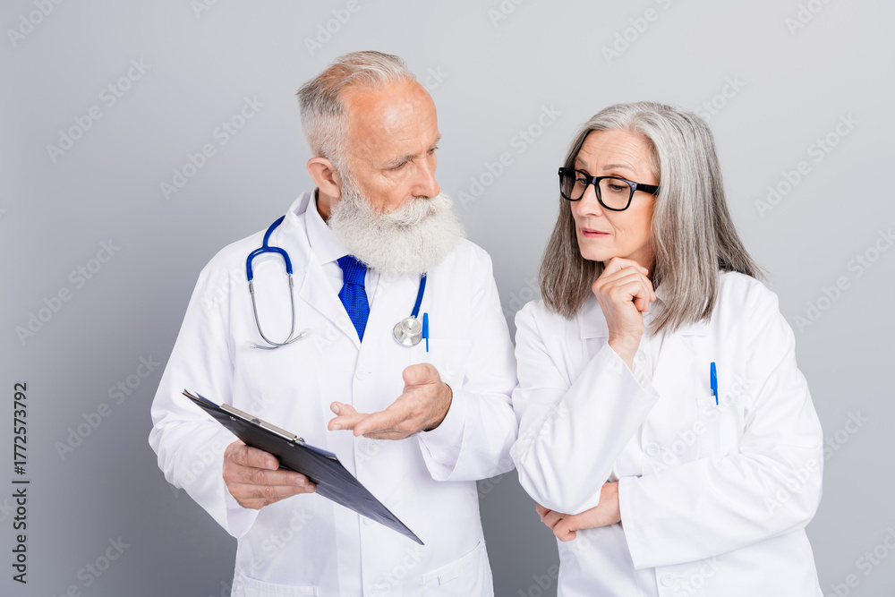 Fototapeta premium Senior doctors discuss patient care and diagnosis in a clinic while reviewing a clipboard and stethoscope