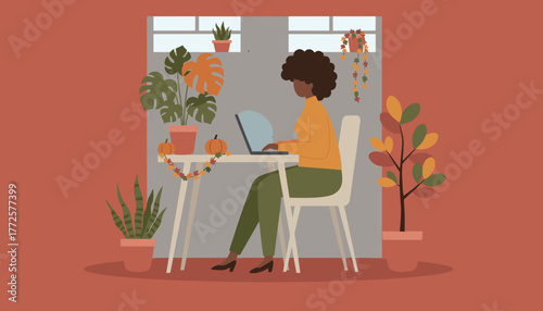 Woman works on laptop at cozy autumn home office desk decorated with plants and pumpkins