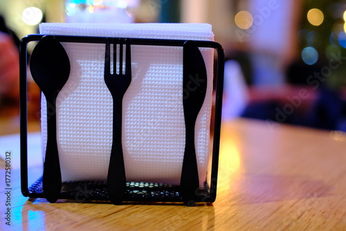 A holder contains white napkins, plus a spoon, fork, and knife.