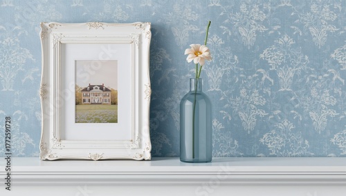 Floral vase and picture frame displayed on a white shelf against a blue wall