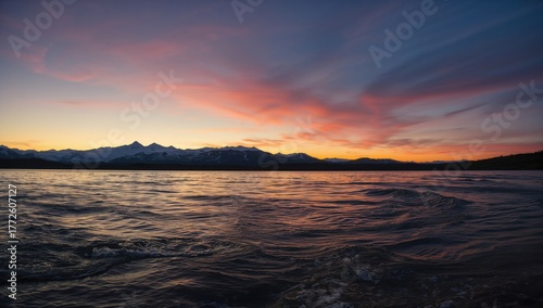 During my holiday, I admired the stunning sunset over the ocean, embraced by the enchanting natural scenery, with water mirroring the vivid hues.