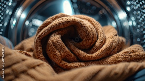 Brown knitted sweater inside a washing machine drum.