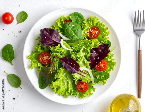 Overhead view of a fresh, vibrant salad on a white plate with cherry tomatoes