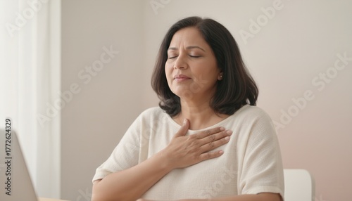 Free Download Middle-aged South Asian woman feeling stressed with her hand on her chest. Mature Indian lady experiencing anxiety or breathing difficulty. Mental health and burnout concept - GFXLoad