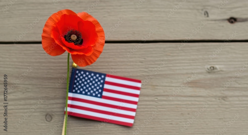 Obraz premium Red poppy flower with a small US flag on a wooden background. Pearl Harbor Remembrance Day, Memorial Day, and Veterans Day concept with copy space for text