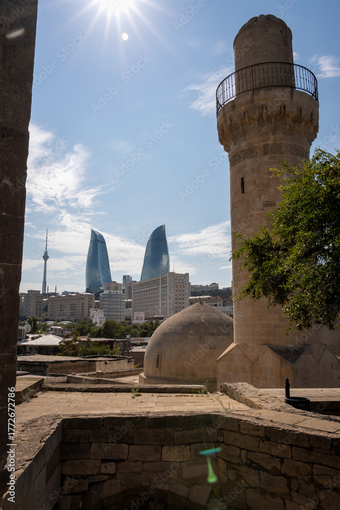 Fototapeta premium Ancient Tower and Modern Skyscrapers Under Sunny Sky. Baku Cityscape with Flame Tower