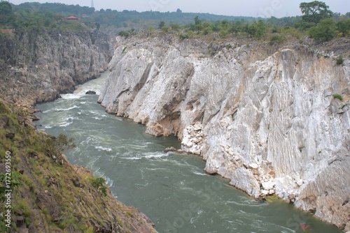 magnificent view of the narmada river carving through towering white marble cliffs at bhedaghat, creating a dramatic natural canyon surrounded by lush greenery