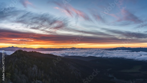 Fototapeta Naklejka Na Ścianę i Meble -  Sun dipping below the peaks of a mountain range.