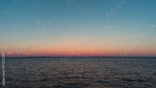Fototapeta Naklejka Na Ścianę i Meble -  Baltic Sea during sunset, showcasing serene water surface texture and vibrant cloud colors, seasonal change