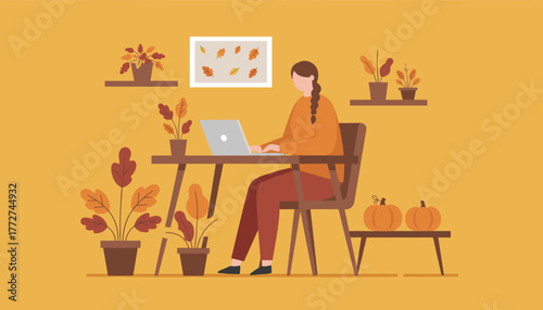 Woman works on a laptop at a cozy autumn desk decorated with fall leaves and pumpkins in a home office